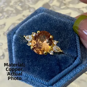 Macro-detail van koperen ring met ovale oranje edelsteen en zirkoon in blauwe doos