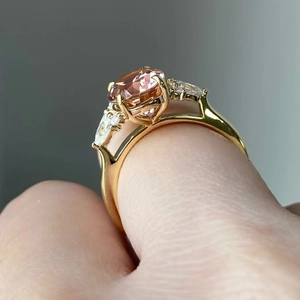 Gouden ring met roze ovale zirkonia en zijdelingse druppelstenen op de hand