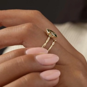 Détail de bague sertie d'une émeraude marquise et anneau torsadé doré élégant