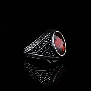 Macro detail of retro black metal ring with a large oval faceted red gemstone and relief