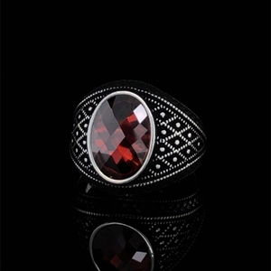 Macro shot of retro silver ring with faceted oval red gemstone and embossed details
