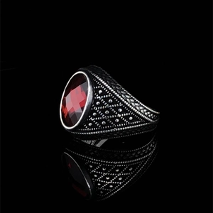 Macro shot of vintage mens ring with red faceted gemstone and oxidized engraving