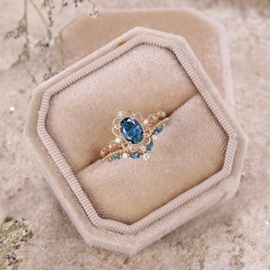 Elegante set nuziale in oro rosa con gemma blu ovale in una scatola di velluto