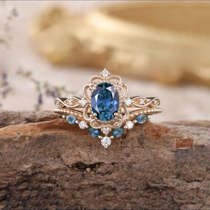 Vista macro dell'anello con gemma blu e filigrana in oro rosa su legno naturale