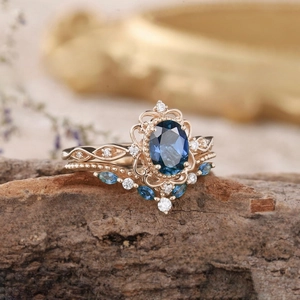 Dettaglio macro di un set di anelli vintage dorati con zirconi blu e incisioni floreali