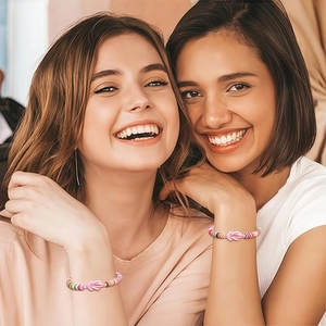 Dettaglio di due donne con braccialetti dell'amicizia in perline colorate e nodo rosa
