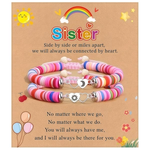 Détail de deux bracelets en perles Heishi colorées avec breloques cœur soleil lune sur carte