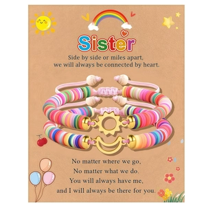 Detail of two handmade woven sister bracelets with gold sun and moon charms on card