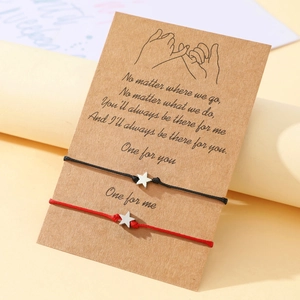 Close-up of handmade star charm braided bracelets on a gift card for couples
