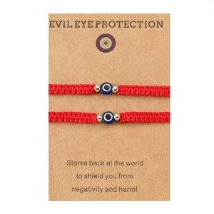 Détail de bracelets de protection mauvais œil rouges tissés sur carte descriptive