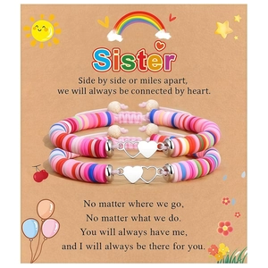 Détail de deux bracelets en perles colorées avec breloques cœur sur une carte cadeau de sœur