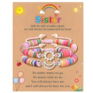 Detail of woven sister friendship bracelets with sun and moon charms on a greeting card