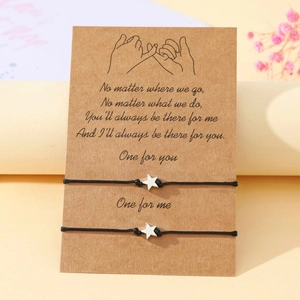 Star charm woven bracelets set on a promise card with warm floral background detail