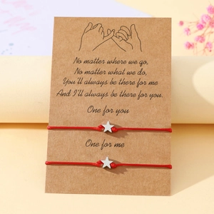 Close-up of star charms on red woven cord bracelets with romantic sentiment card