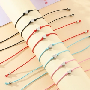 Détail de bracelets tressés colorés avec pendentifs cœur sur un support de présentation