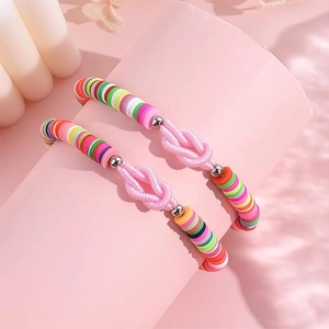Dettaglio di bracciali colorati in argilla polimerica con nodo rosa intrecciato a mano