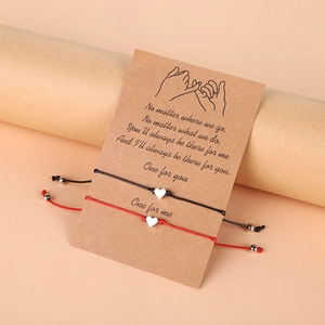 Détail de bracelets cœur tressés rouge et noir sur une carte de message