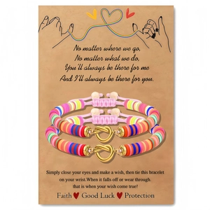 Handgemaakte kleurrijke kleikralen armbandenset met gouden hartbedeltje op een cadeaukaart