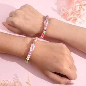 Dettaglio del bracciale fatto a mano con perline heishi colorate e nodo rosa decorativo