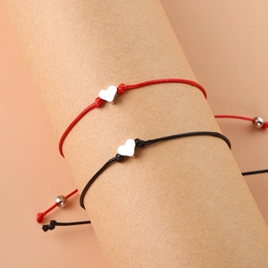 Détail de bracelets tressés rouges et noirs avec pendentif cœur et perles argentées