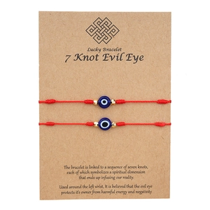 Détail de deux bracelets 7 nœuds rouges avec œil maléfique et perles bleues sur carte