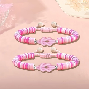 Dettaglio di due braccialetti fatti a mano in argilla rosa con nodi regolabili e ombre di foglie