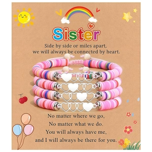 Gros plan de quatre bracelets de sœur avec perles heishi et breloques cœur en métal