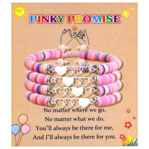 Détail de quatre bracelets en perles d'argile polymère avec pendentifs cœur sur carte cadeau