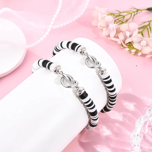 Detail van kralenarmbanden met zwart-witte kleikralen en zilveren knoopvormige sluitingen