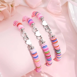 Gros plan de trois bracelets en perles heishi colorées avec cœurs en argent