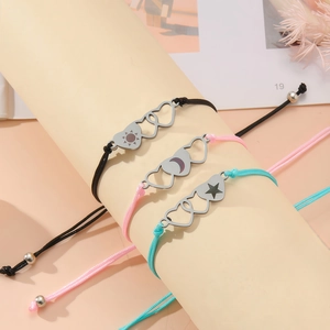 Detailed view of sun moon and star engraved hearts on colorful woven rope bracelets