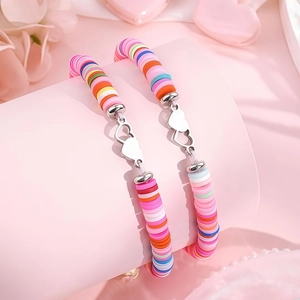 Détail de bracelets en perles Heishi colorées avec breloques cœur argentées sur présentoir
