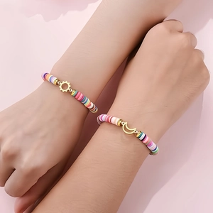 Detail of sun and moon charms on colorful bohemian style clay bead bracelets worn on wrist
