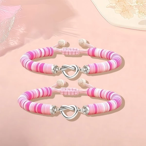 Detail van roze en witte klei kralen armbanden met een hartvormige knoopsluiting