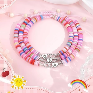 Détail de trois bracelets en argile colorée avec breloques cœur soleil lune sur tissu