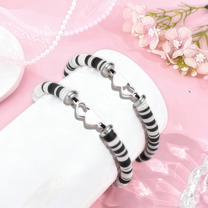 Détail de bracelets en perles d'argile faits main avec breloques cœur argenté sur soie