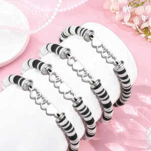 Détail de quatre bracelets faits main en perles heishi noires et blanches avec cœurs