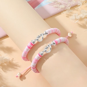 Detail van roze Heishi-kralenarmbanden met zilveren oneindigheidsknoop en verstelbaar koord