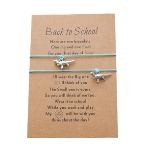 Detail der Dino-Anhänger an hellblauen Kordelarmbändern mit Back-to-School-Karte