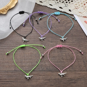 Set mit verstellbaren Dinosaurier-Armbändern in fünf Farben auf einem hölzernen Hintergrund