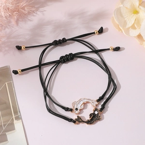 Close-up of yin yang koi fish bracelets with black woven rope and gold-edged charms
