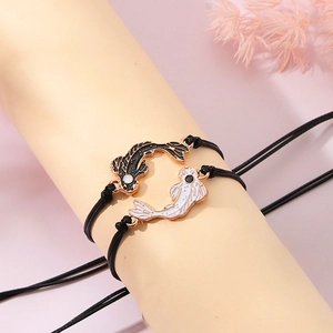 Close-up of woven Yin Yang koi fish bracelets for friends on a soft display