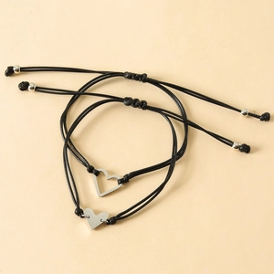 Detail of adjustable black woven bracelets featuring silver heart pendants and sliding knots