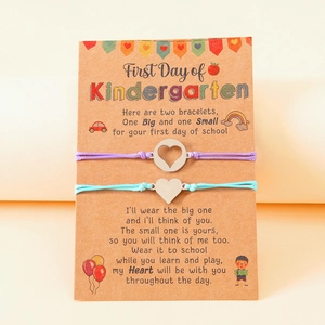 Two woven bracelets with heart pendants on a first day of school card for mother and daughter