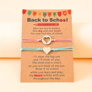 Detail of pink and blue woven bracelets with heart charms on first day of school card