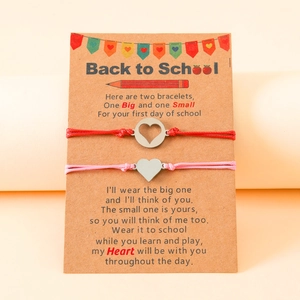 Close-up of mother and daughter back to school bracelets with heart charms on card