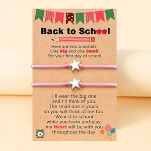 Detailansicht von zwei rosa Webarmbändern mit Silbersternen auf einer Schulstart-Geschenkkarte