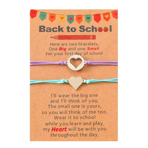 Detail of woven mother and daughter bracelets with heart charms on a themed gift card