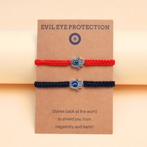 Détail de bracelets Hamsa tressés rouges et noirs avec breloques œil bleu