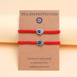 Détail de bracelets Evil Eye tressés rouges avec main de Hamsa sur carte support